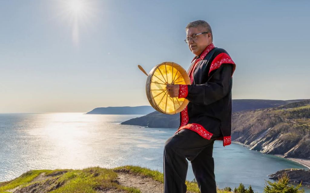 Indigenous cultural experience in Cape Breton with traditional drumming overlooking coastal cliffs