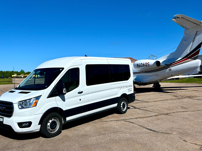 Ford Transit passenger van beside private jet for airport transfer in Cape Breton
